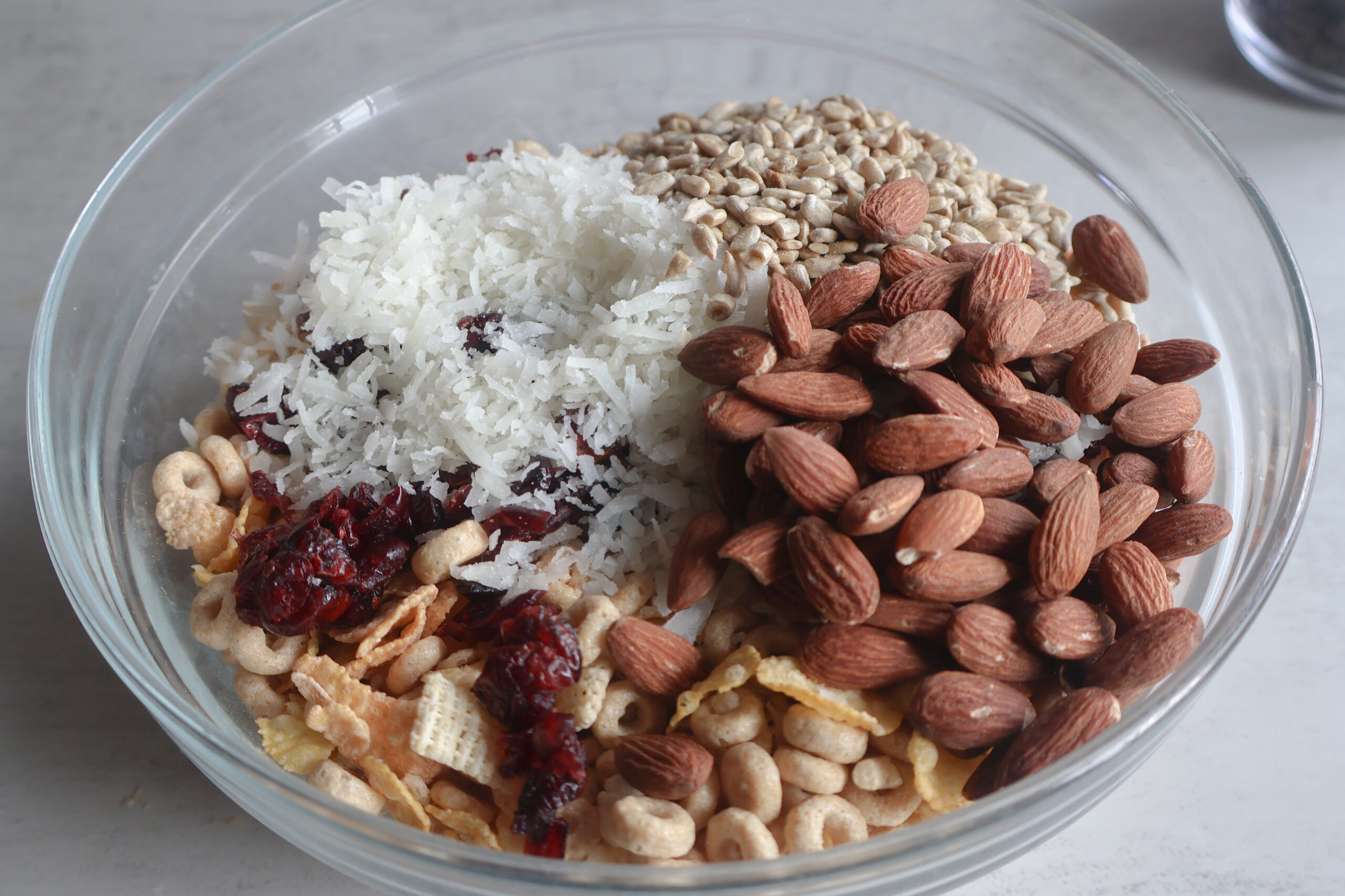 Easy Homemade Cereal Trail Mix in a bowl with almonds, sunflower seeds, coconut, and cranberries.