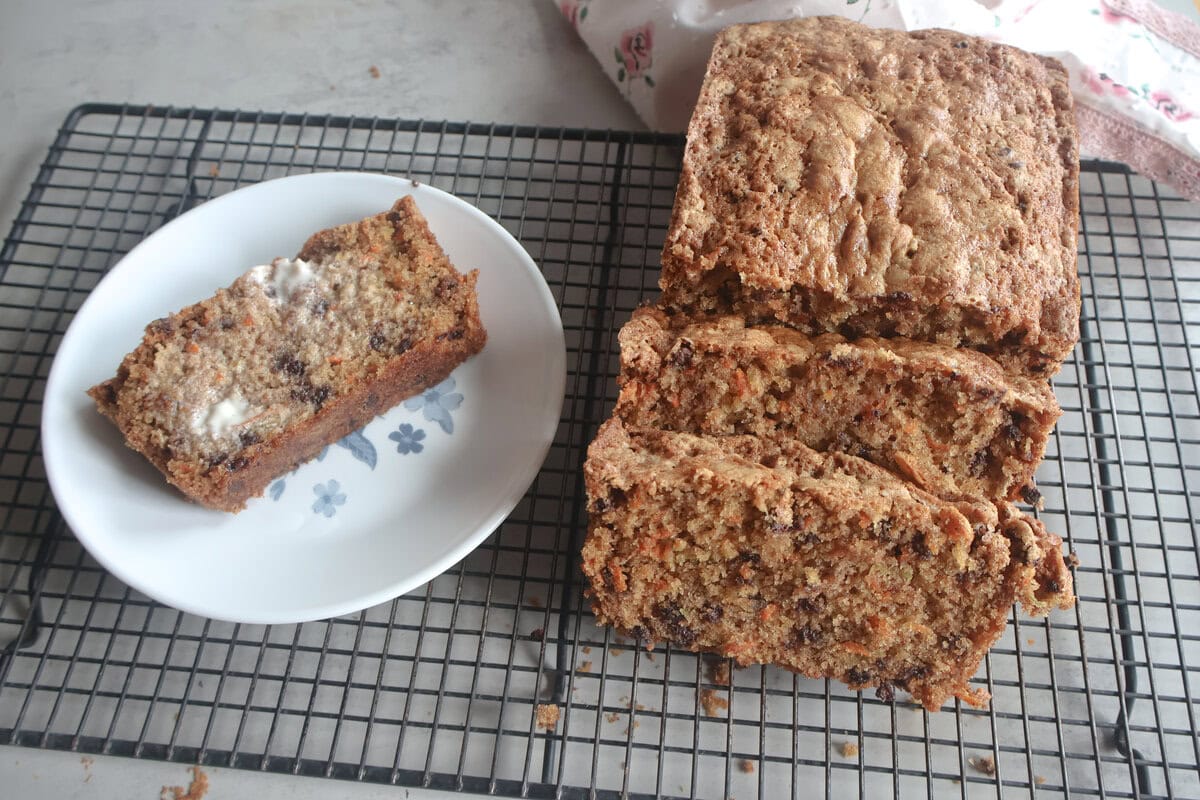 Chocolate Chip Zucchini Carrot Bread on a cooling rack and a slice on a small plate.
