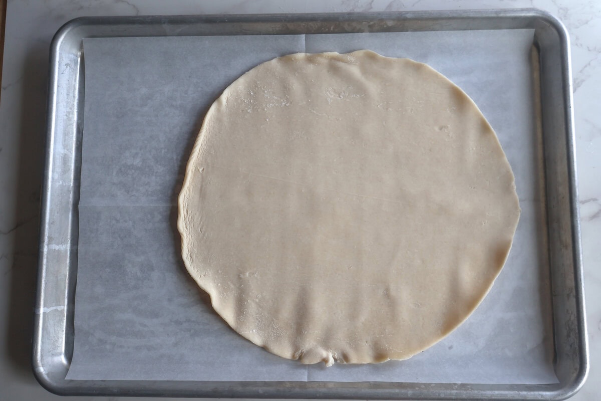 Rolled out pie crust on a sheet pan.