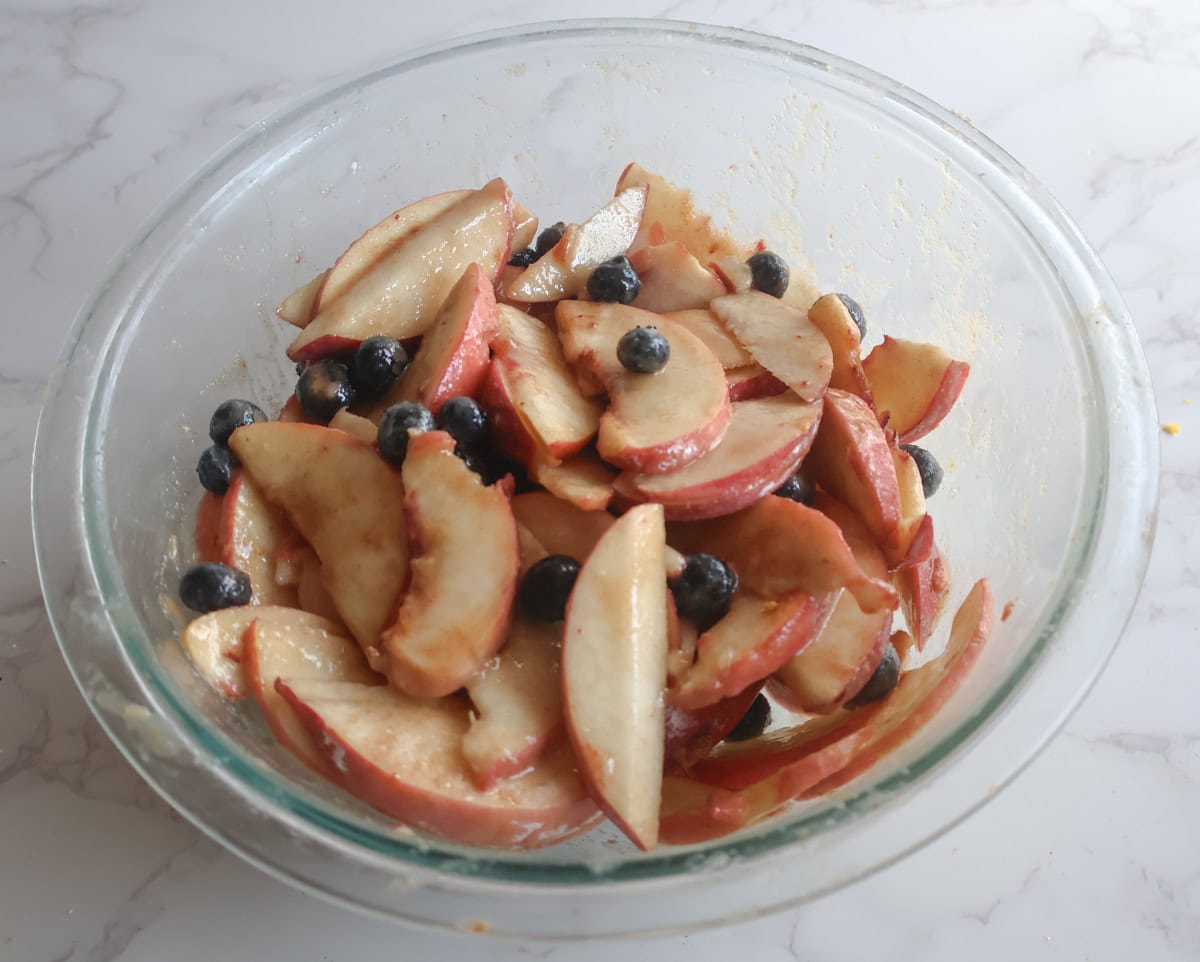 sliced peaches and blueberries mixed in a glass bowl.