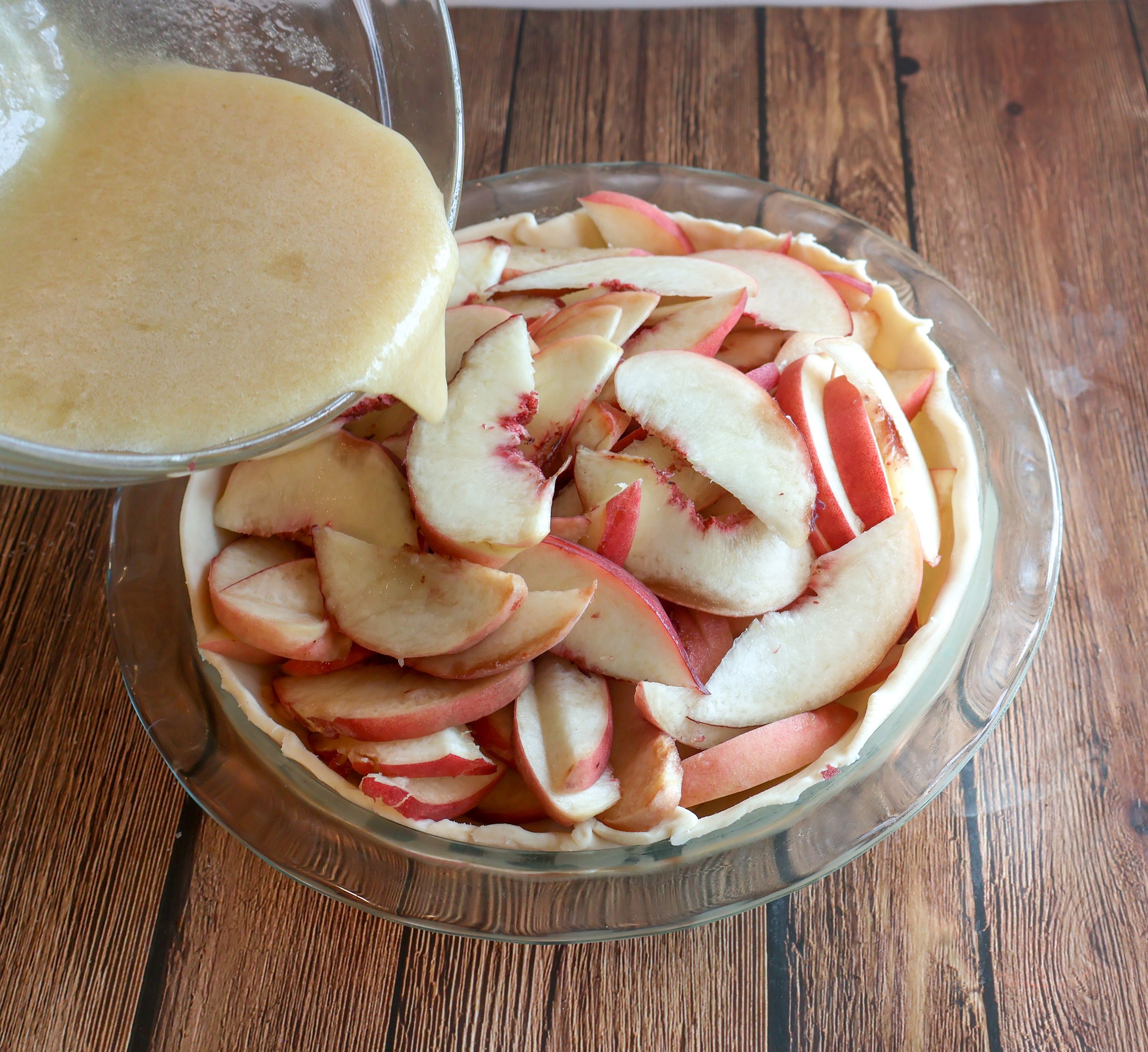 custard being poured over the peaches.