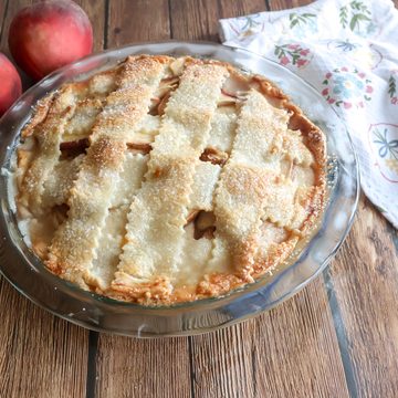 Fresh Peach Custard pie with peaches and a tea towel.