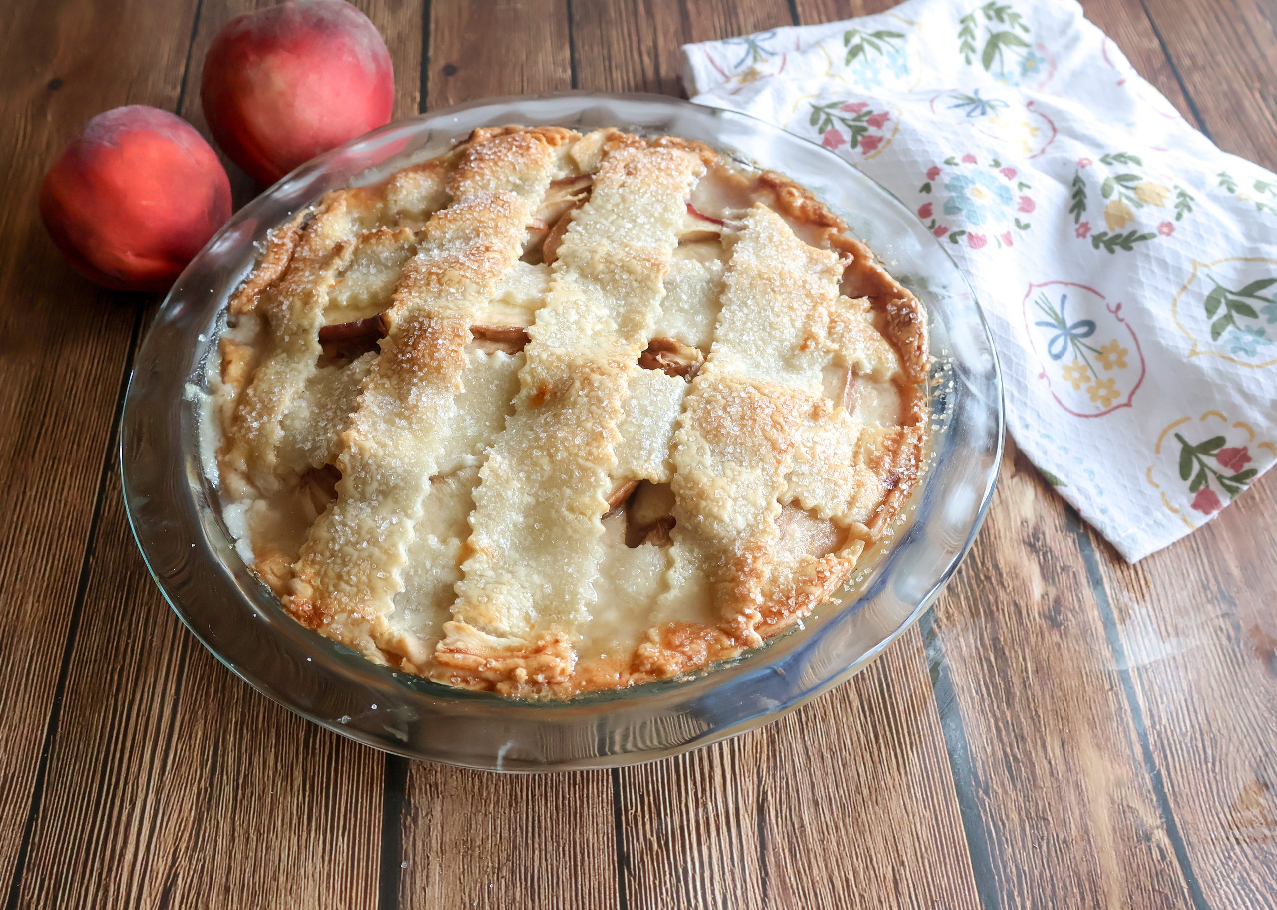 whole fresh custard pie in a glass pie dish with peaches.