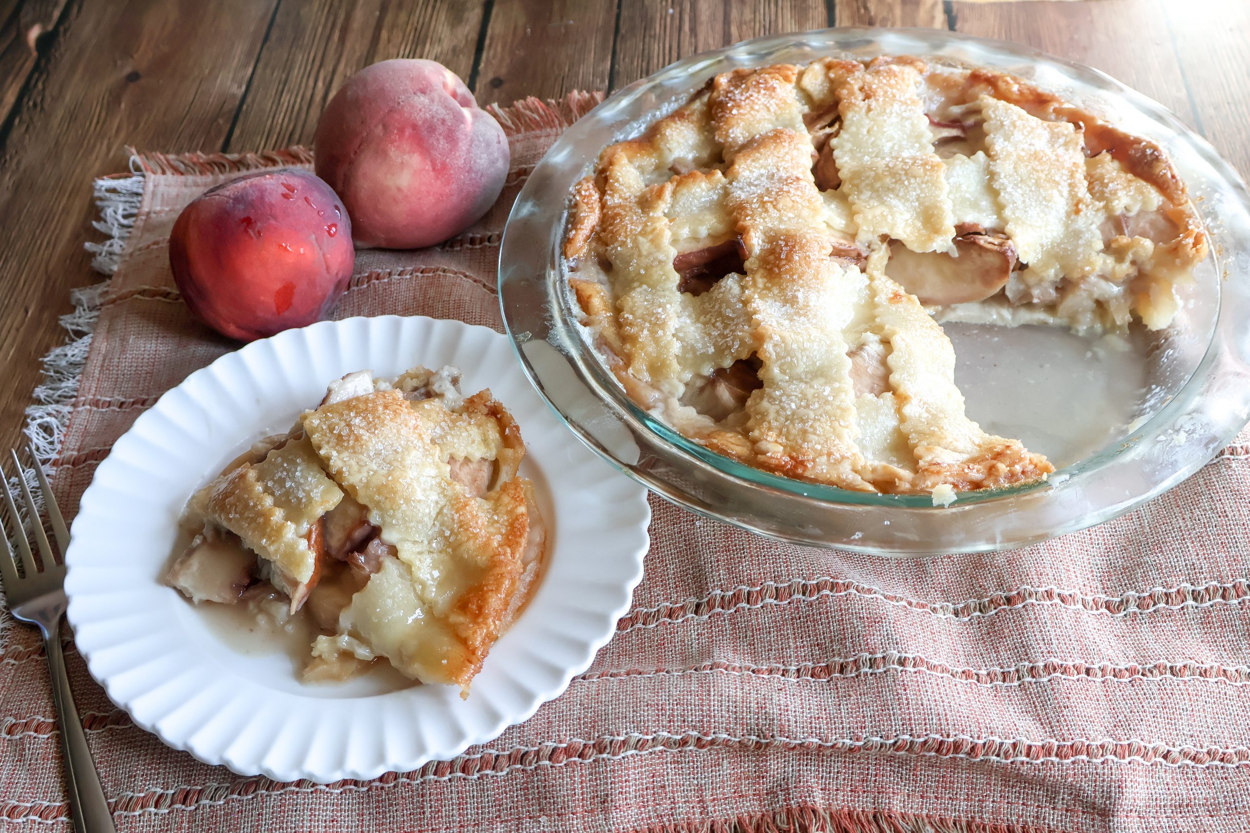 Fresh peach custard pie with a piece on a plate with peaches.