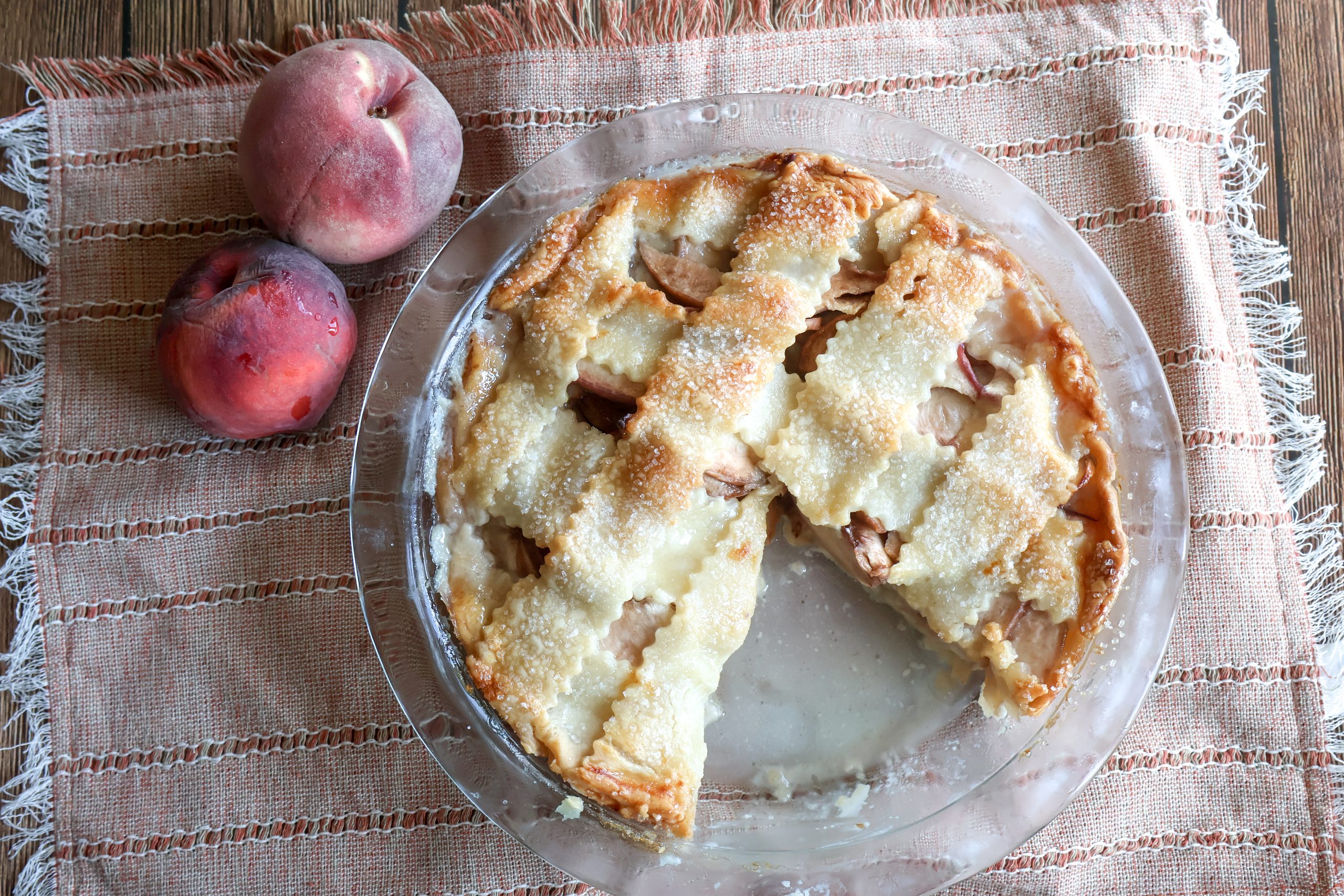 Fresh Peach Custard Pie with a piece missing with fresh peaches.