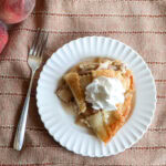 Fresh peach custard pie on a white plate with a fork.