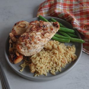 vidalia onion almond chicken on a plate with rice and green beans.
