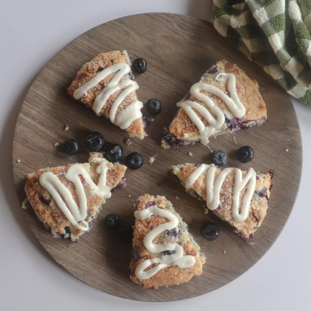 Blueberry white chocolate scones on a brown plate with fresh blueberries.