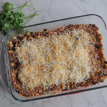 cheesy mexican beef and rice casserole in a clear dish with cilantro.