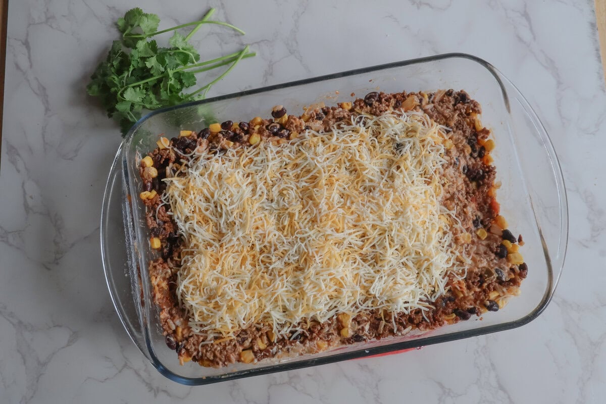 cheesy mexican beef and rice casserole with shredded cheese and cilantro.