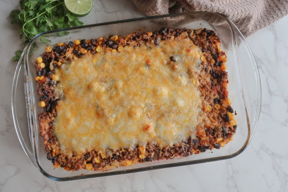 cheesy mexican beef and rice casserole in a clear dish with cilantro and lime.