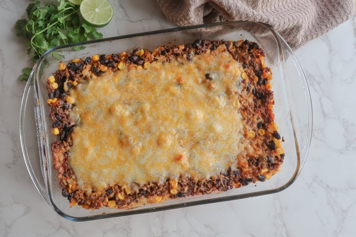 cheesy mexican beef and rice casserole in a clear dish with cilantro and lime.