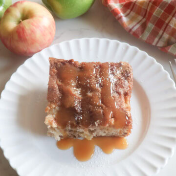 apple cake on a white plate with caramel sauce and apples.