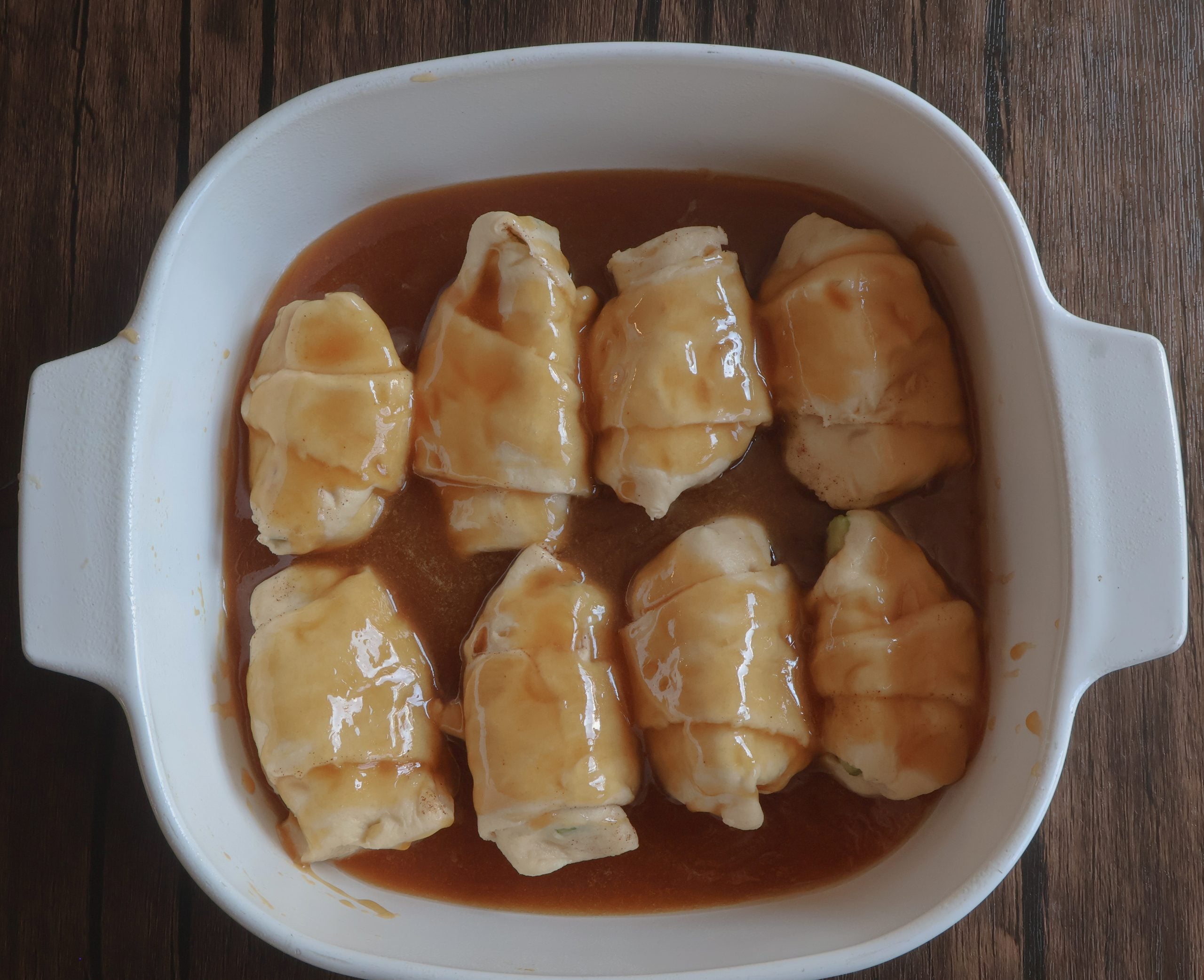 caramel apple dumplings in a white casserole dish.