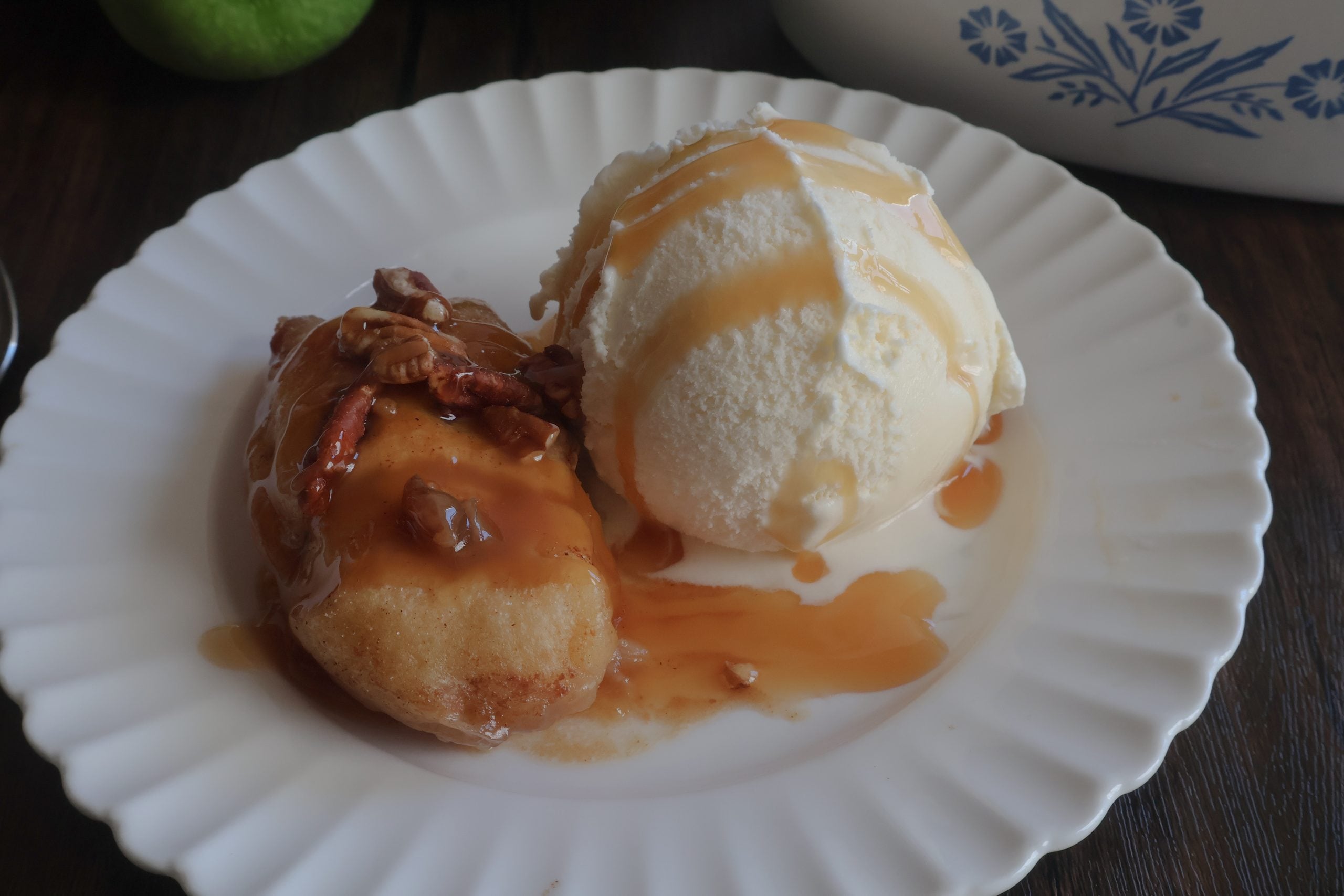 caramel apple dumpling on a white plate with ice cream.
