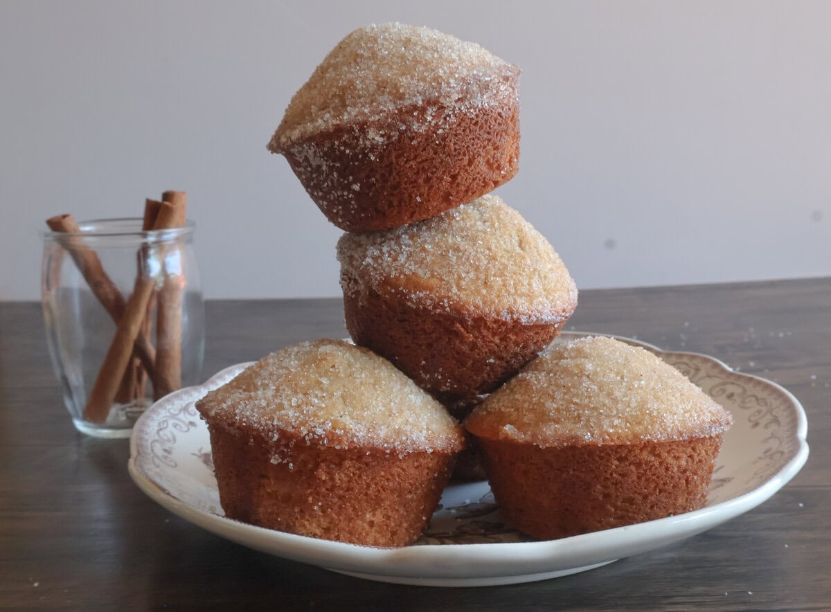 apple cider donut muffins stacked on top of each other with cinnamon sticks.