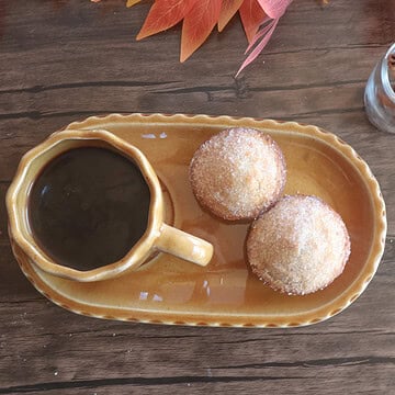 apple cider donut muffins on a tan plate with a cup of coffee.