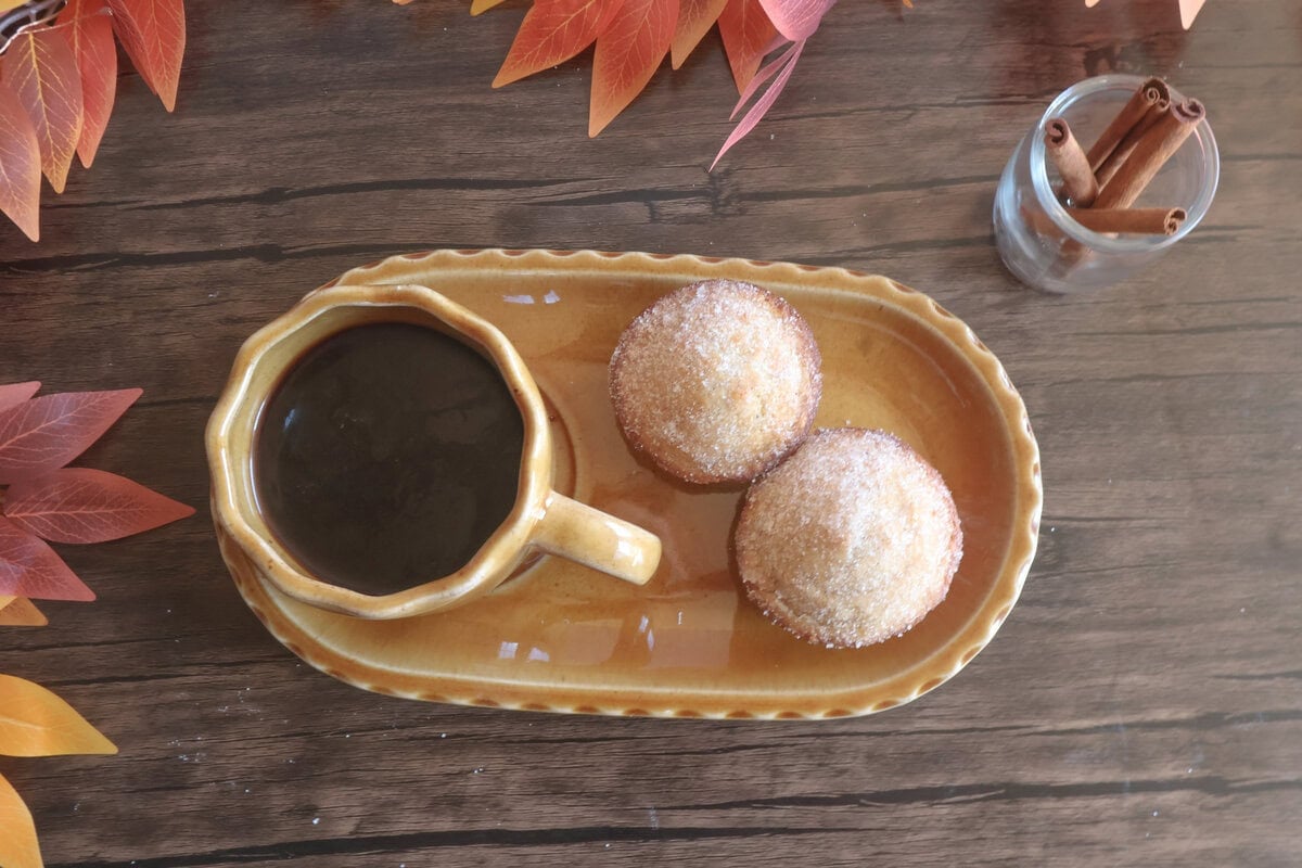 apple cider donut muffins on a tan plate with a cup of coffee.