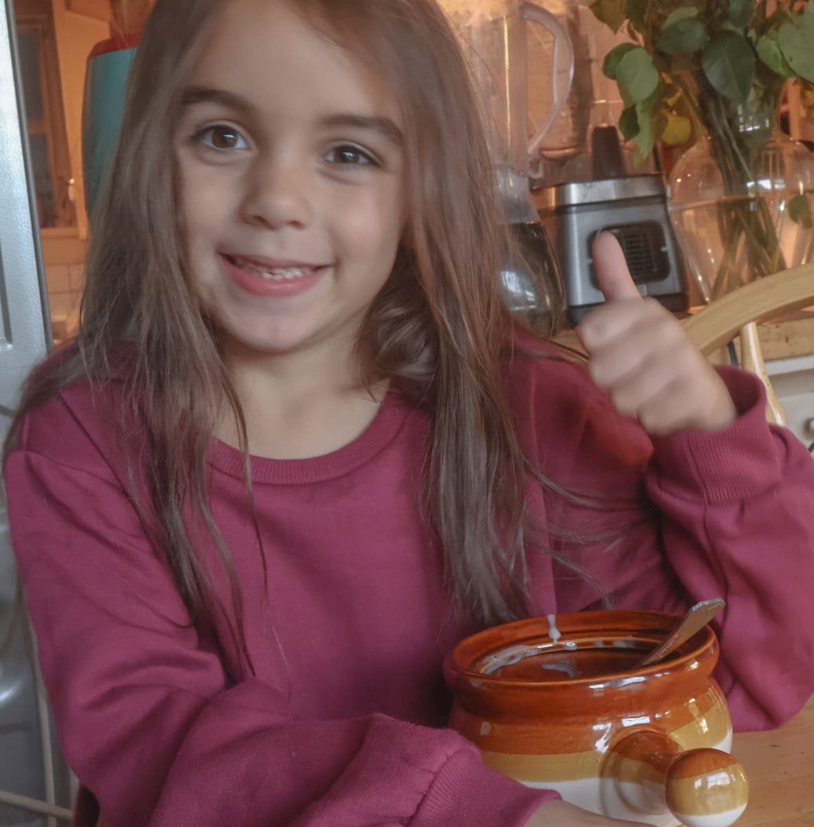 My daughter enjoying the soup in a brown crock.