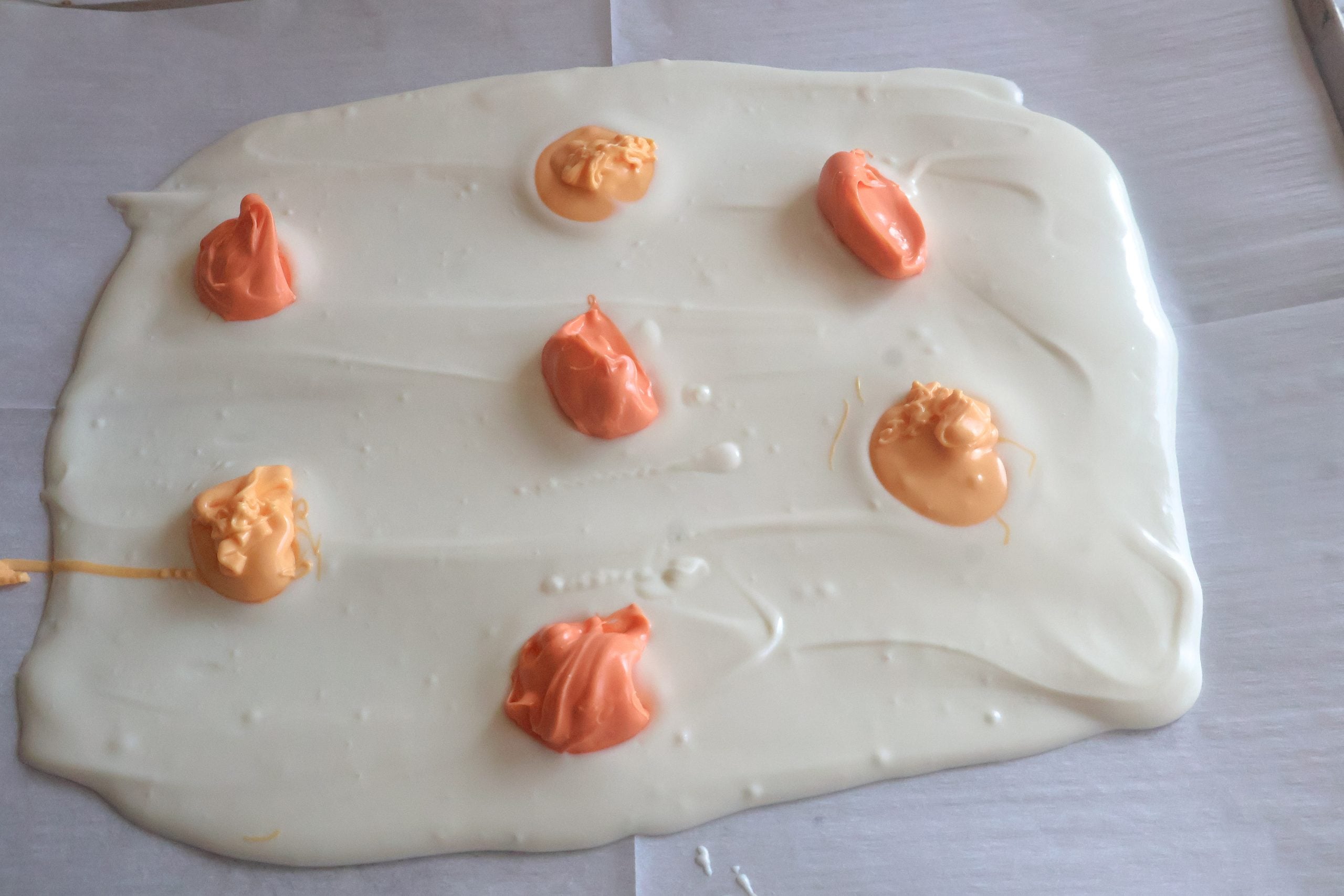 spoonfuls of yellow and orange candy on the white chocolate.