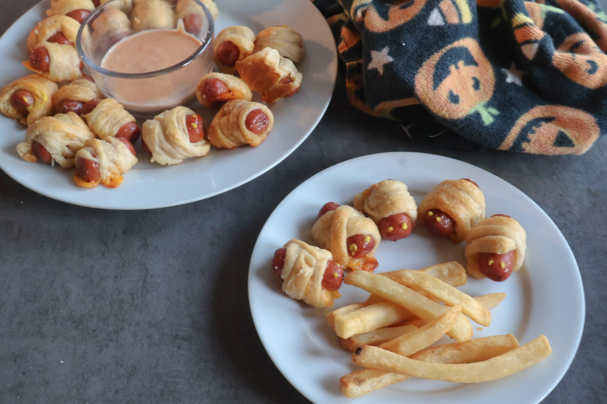 mini mummy hot dogs on a platter and a white plate with fries.